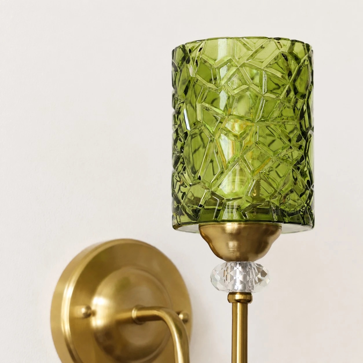 Green faceted glass cylinder shade on a vintage wall sconce