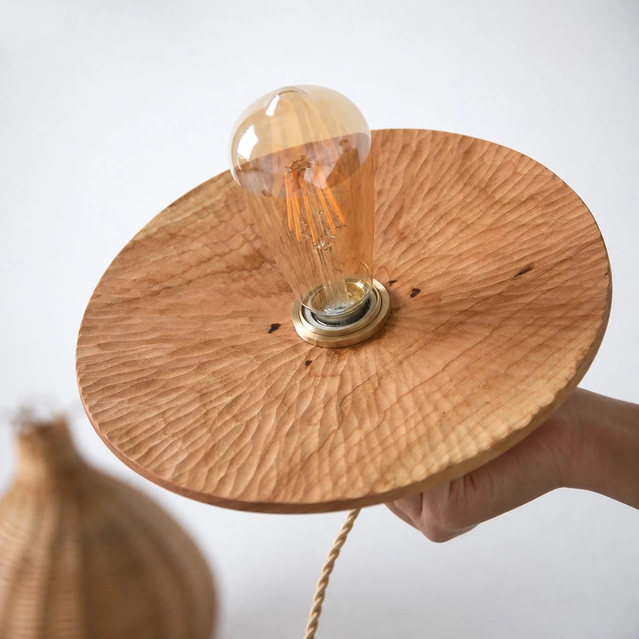 Hand held view of the thin round carved wooden lamp shade