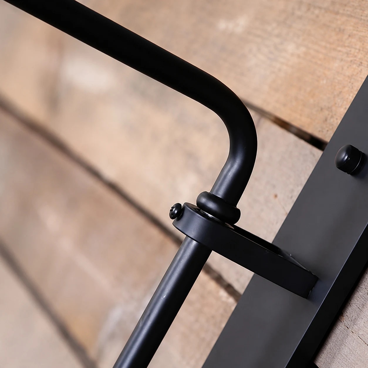 Curved dark bronze wall lamp arm and wall plate detail