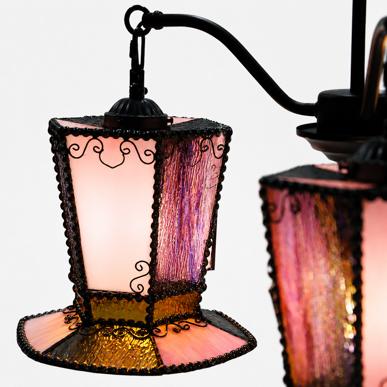 Close-up of the chandelier glass shade, black metal edging, and scrollwork detail