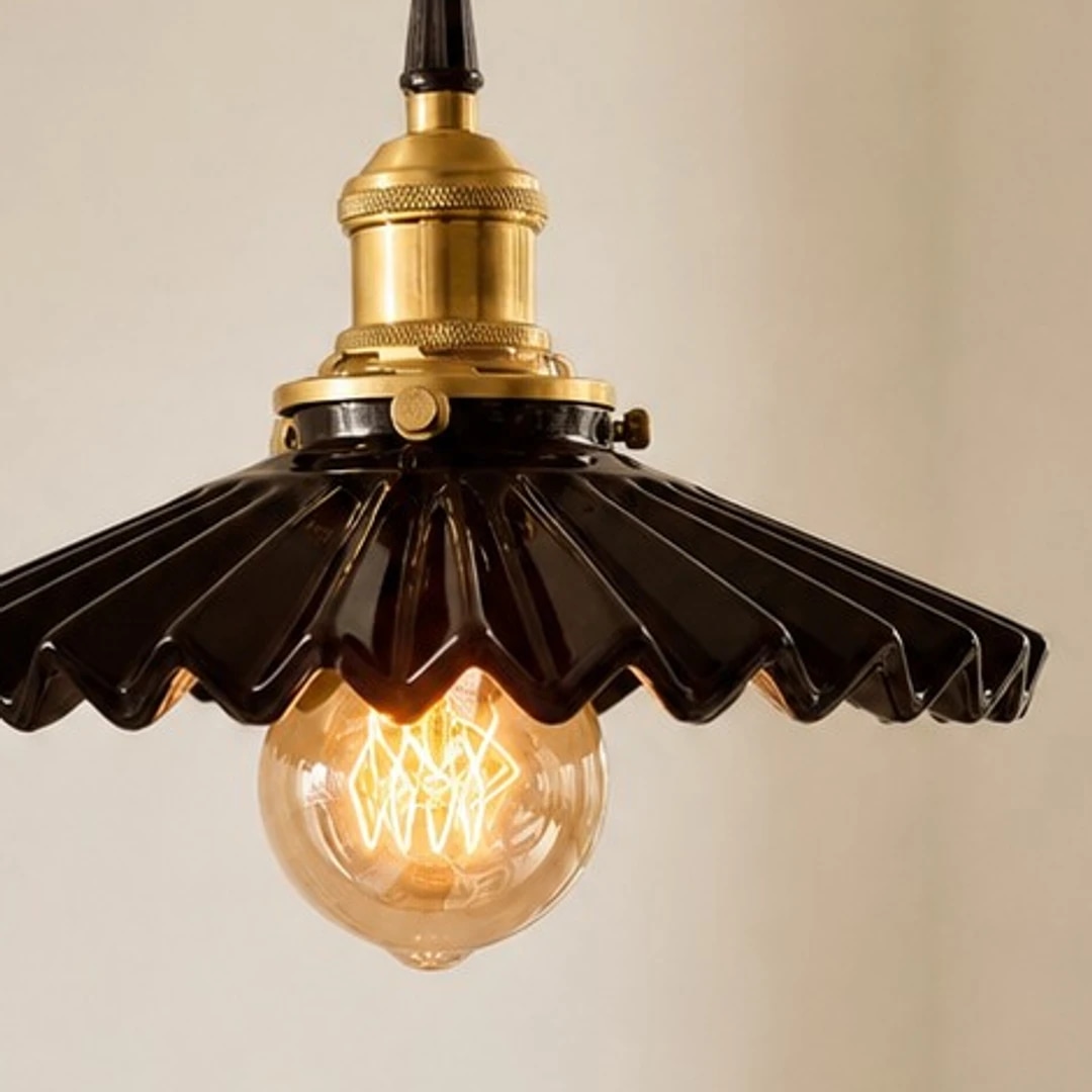 Warm exposed bulb beneath the ceramic pendant shade