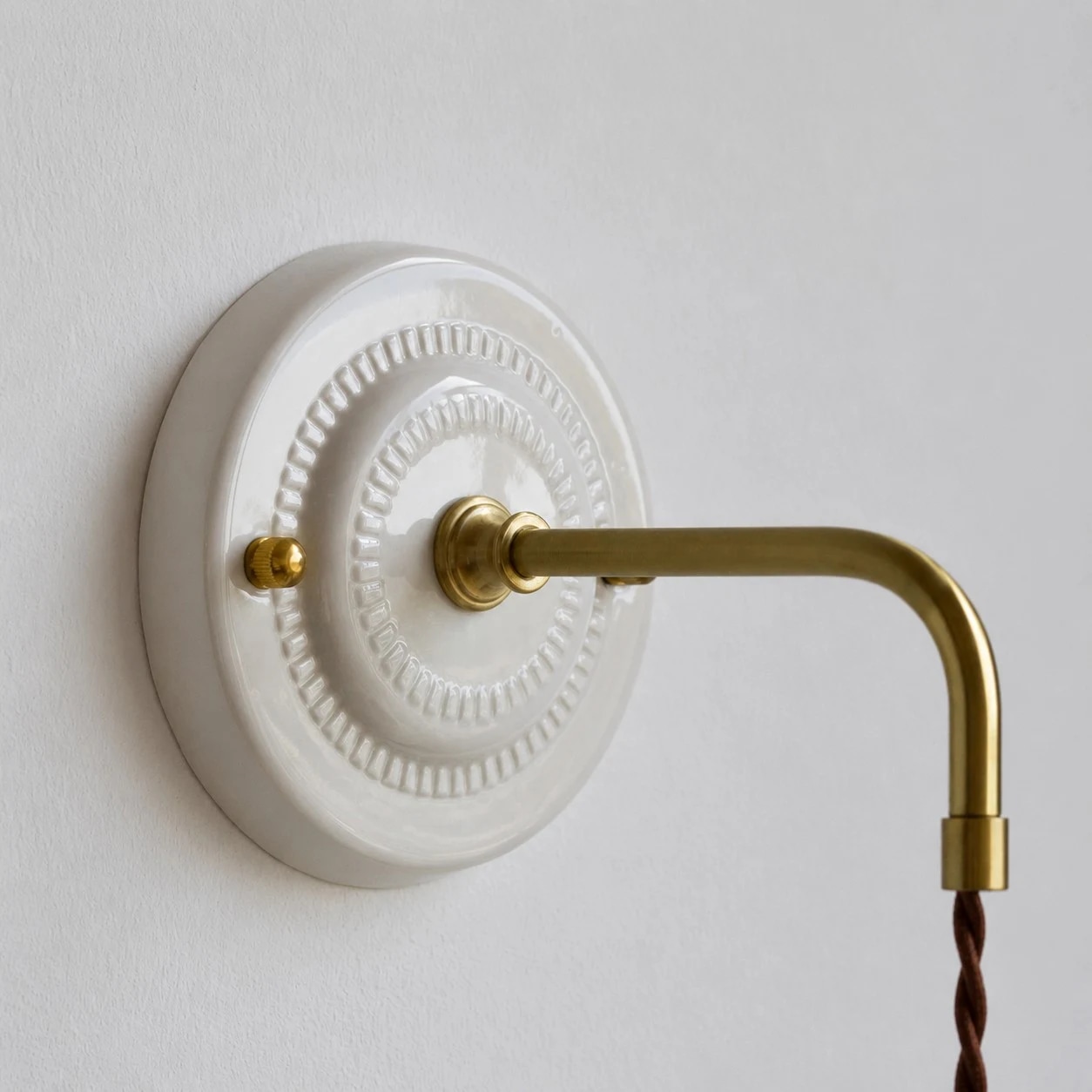 Ceramic wall plate and brass toned lamp arm detail