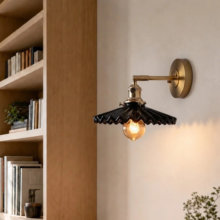 Black pleated wall sconce near a bookshelf