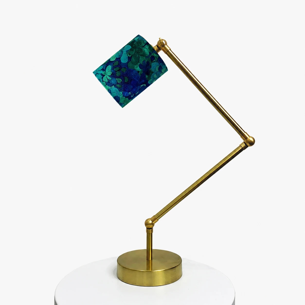 Full view of the brass-tone adjustable table lamp with blue green floral shade
