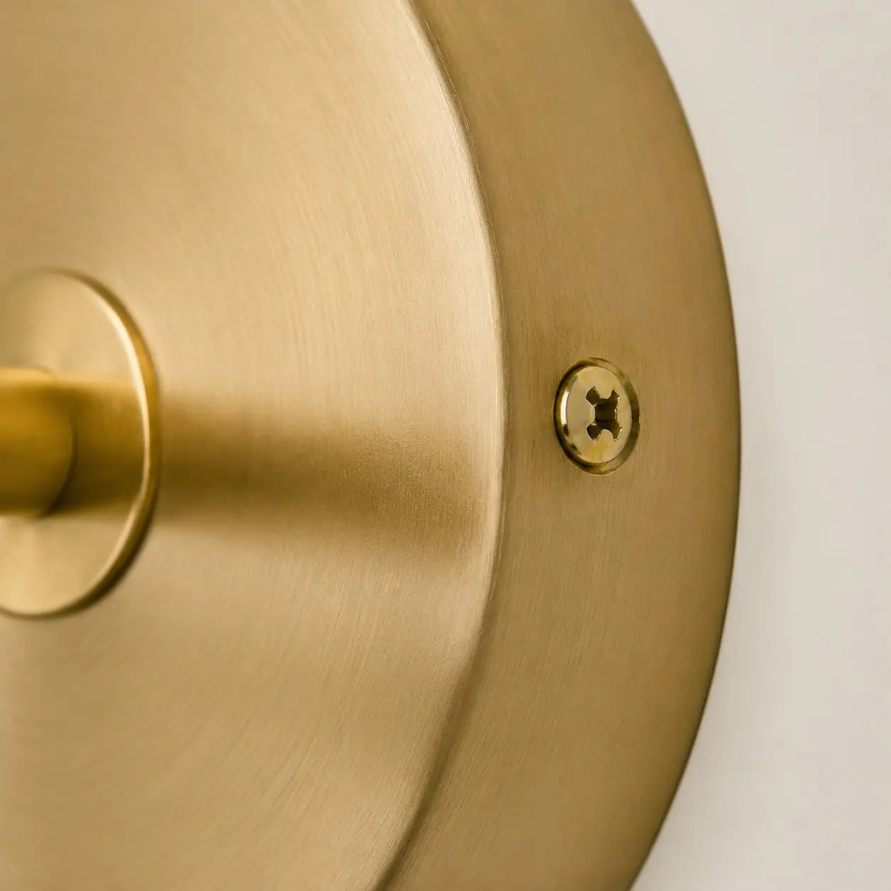 Detailweergave van de ronde achterplaat met geborstelde messingkleurige afwerking.