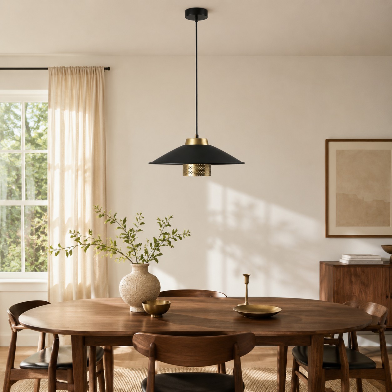 Luminária pendente preta e dourada centralizada acima de uma mesa de jantar redonda de nogueira.