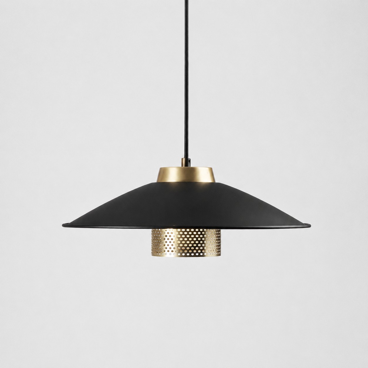 Luminária pendente em metal preto e latão antigo com ampla cúpula cônica sobre fundo branco.