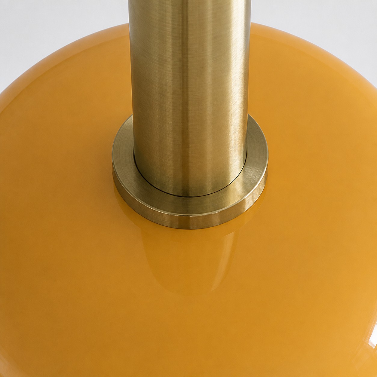 Visão aproximada da conexão entre o suporte de latão e a cúpula de vidro amarelo.