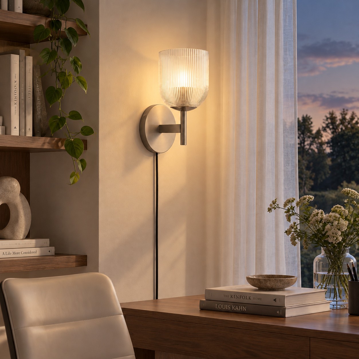 The same desk with a ribbed-glass sconce glowing at dusk