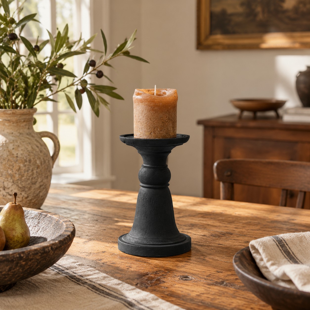 Un bougeoir en bois noir centré sur une table en bois entre un vase et un bol