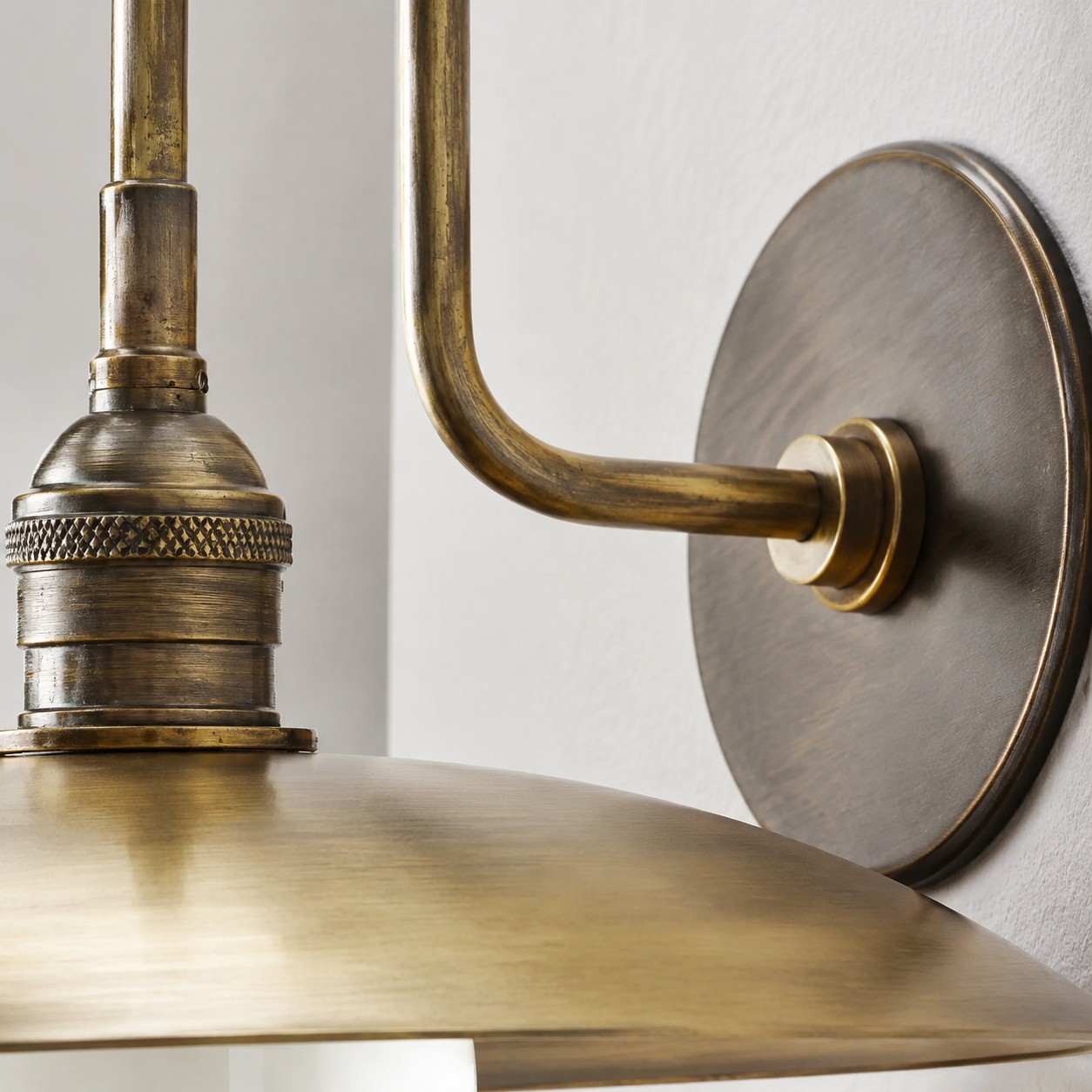 Gedetailleerd zicht op de fitting van de Cantina-lamp en de gebogen antieke messing arm.