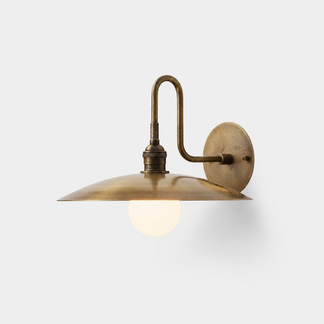 Antieke messing wandlamp van Cantina met gebogen arm en brede metalen kap.