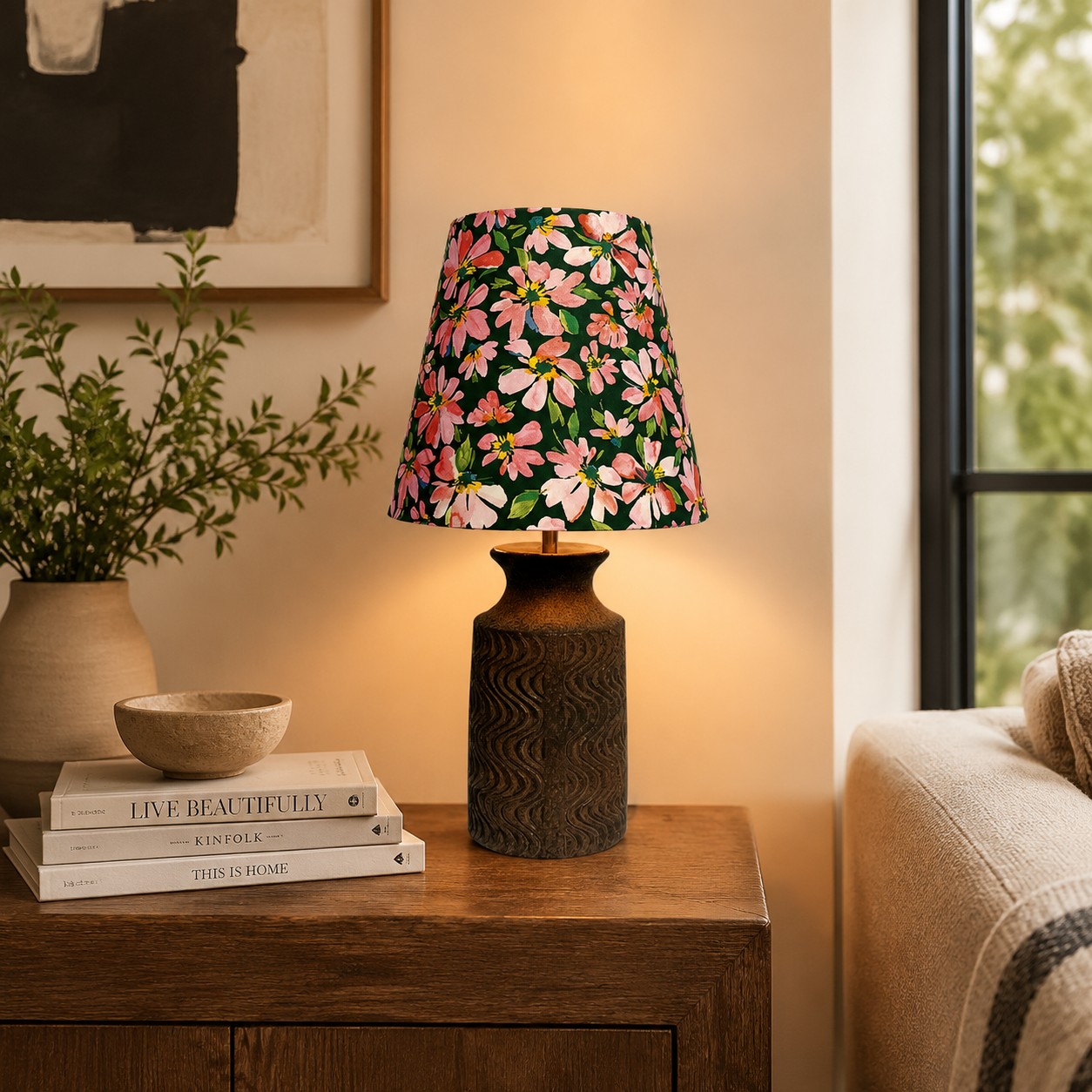 Lampe de table en céramique à motif floral, éclairée à côté d'un canapé sur une table d'appoint en bois.