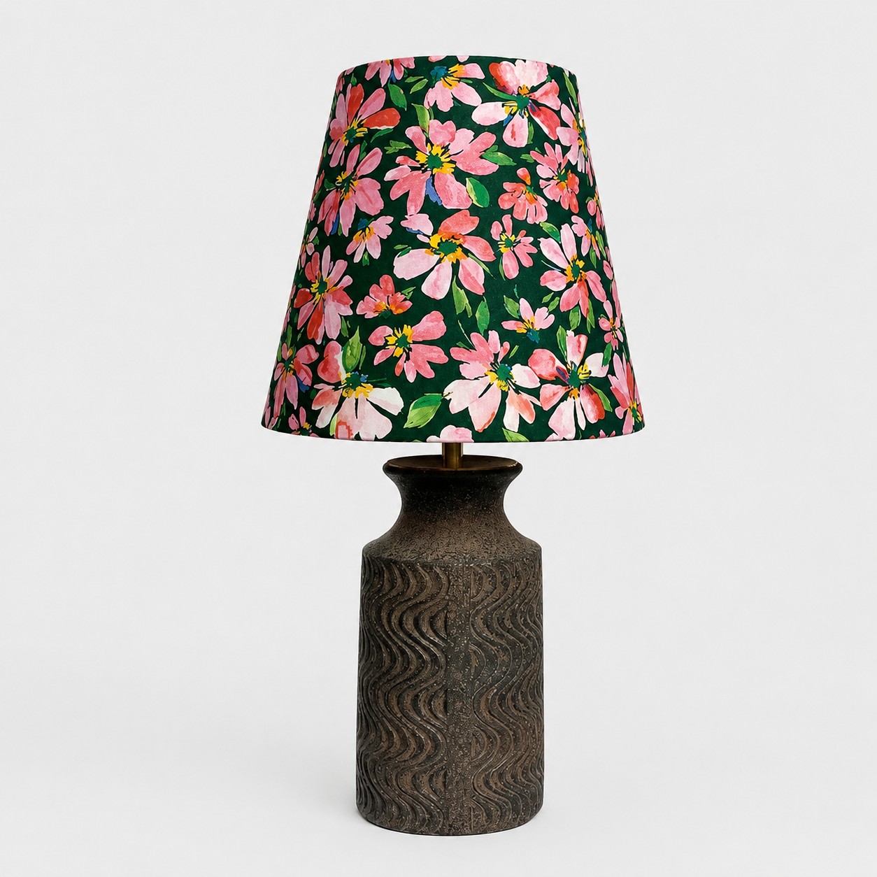 Vue de face d'une lampe de table en tissu à motifs floraux avec un pied en céramique foncée texturée